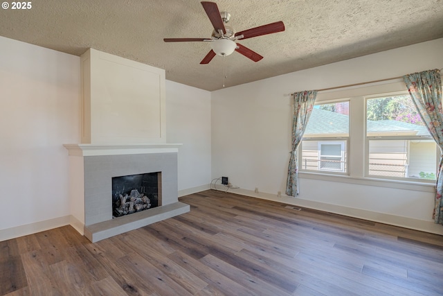 7906 SE Woodstock Blvd, Portland, OR 97206 - unfurnished living room featuring a ceiling fan, wood finished floors, a fireplace with raised hearth, a textured ceiling, and baseboards