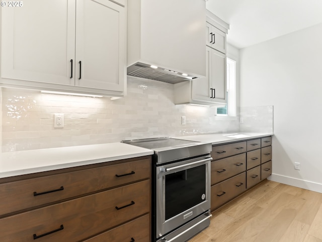 1208 N 44th Pl, Ridgefield, WA 98642 - kitchen featuring decorative backsplash, stainless steel electric range, light countertops, custom exhaust hood, and light wood finished floors