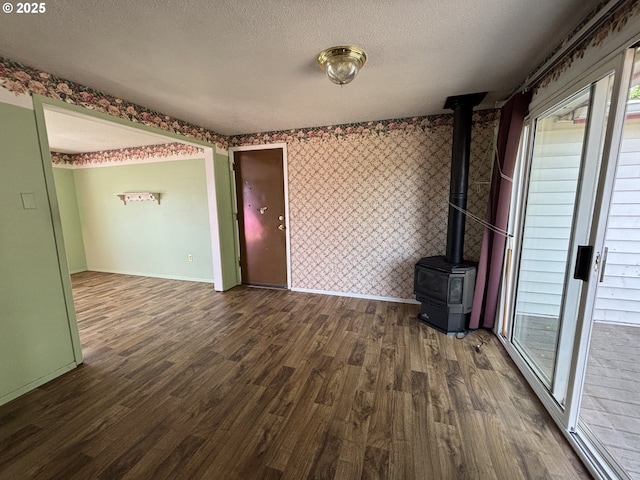 2312 N Pine St, La Grande, OR 97850 - spare room featuring wood finished floors, a wood stove, a textured ceiling, healthy amount of natural light, and wallpapered walls