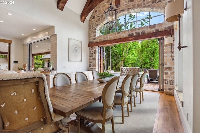 dining space with light wood-type flooring, high vaulted ceiling, beamed ceiling, and a wealth of natural light