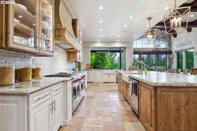 kitchen featuring hanging light fixtures, a large island with sink, light stone counters, appliances with stainless steel finishes, and white cabinets