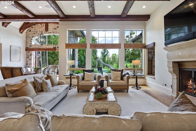 living room featuring light hardwood / wood-style floors, an inviting chandelier, a high ceiling, and beam ceiling