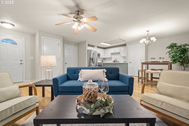 living room featuring ceiling fan with notable chandelier and light wood-type flooring