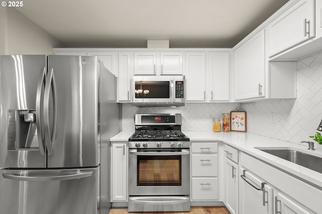 kitchen with stainless steel appliances, white cabinetry, tasteful backsplash, and sink