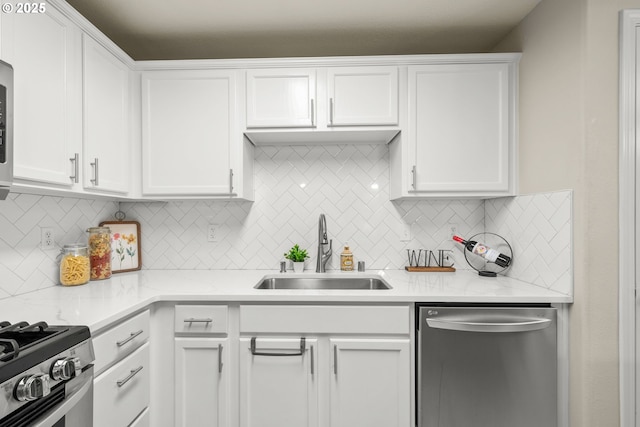 kitchen with stainless steel appliances, white cabinetry, sink, and backsplash