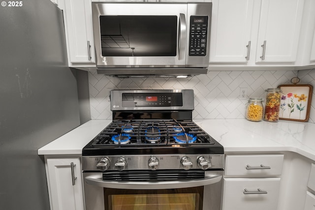 kitchen featuring light stone counters, stainless steel appliances, decorative backsplash, and white cabinets