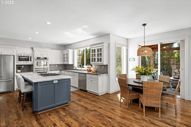 kitchen featuring built in appliances, white cabinetry, a kitchen island, backsplash, and recessed lighting
