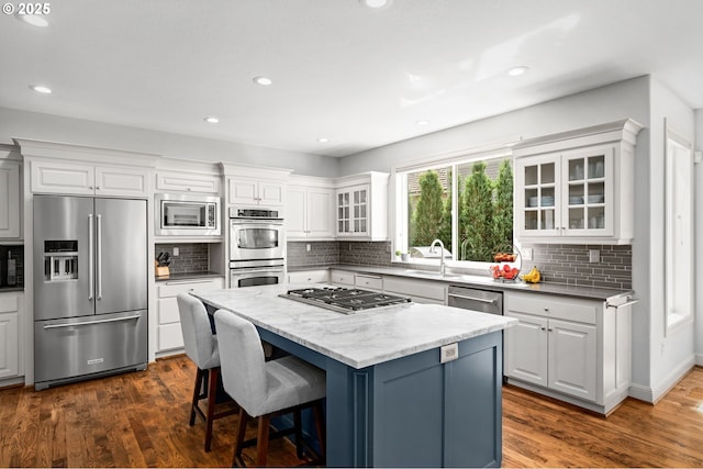 kitchen featuring stainless steel appliances, a kitchen island, a sink, white cabinetry, and recessed lighting