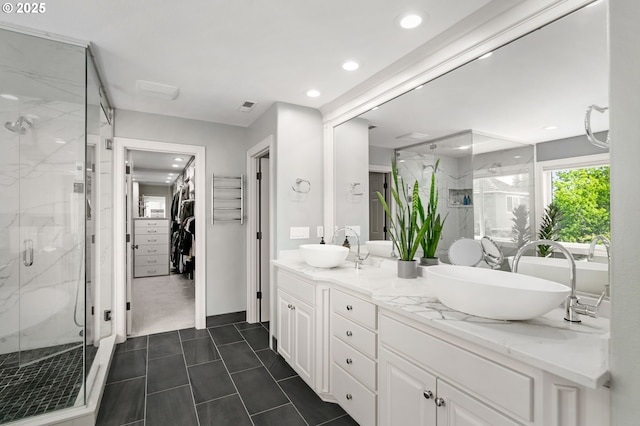 bathroom featuring a marble finish shower, a spacious closet, double vanity, and recessed lighting