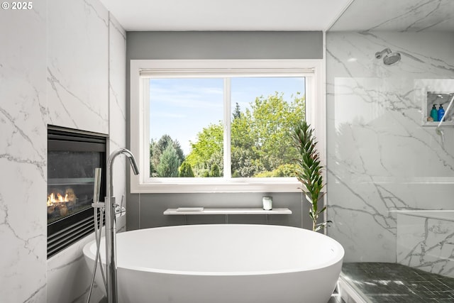 bathroom with a fireplace, a freestanding tub, and plenty of natural light