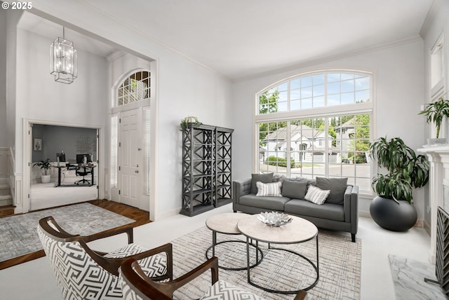 living area featuring a towering ceiling, crown molding, a chandelier, and wood finished floors