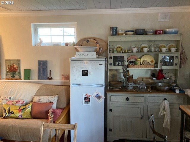 kitchen featuring freestanding refrigerator, wood ceiling, and ornamental molding