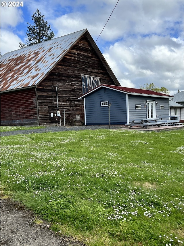 rear view of property featuring french doors, a barn, an outbuilding, and a yard