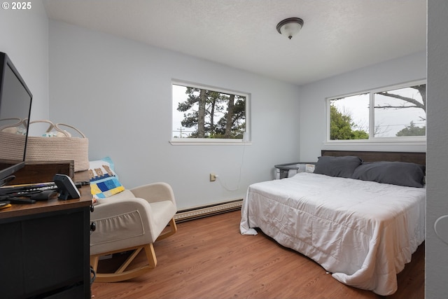 bedroom with a baseboard heating unit and hardwood / wood-style floors