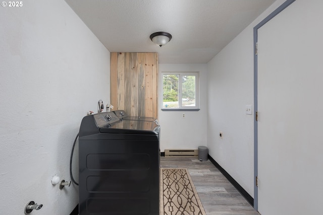 laundry room featuring washer and dryer, a baseboard heating unit, a textured ceiling, and light hardwood / wood-style flooring