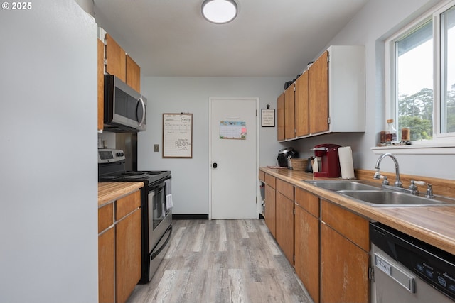 kitchen with appliances with stainless steel finishes, light hardwood / wood-style floors, and sink