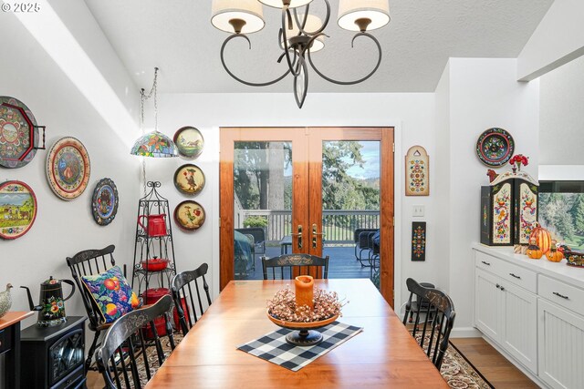 dining area featuring french doors, a textured ceiling, an inviting chandelier, and light hardwood / wood-style flooring