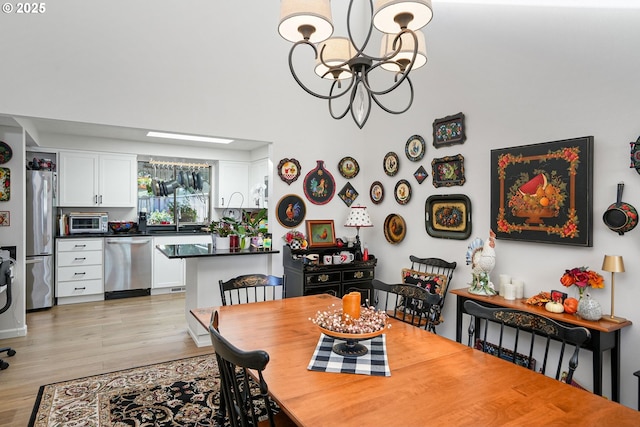 dining room with light hardwood / wood-style floors, an inviting chandelier, and sink