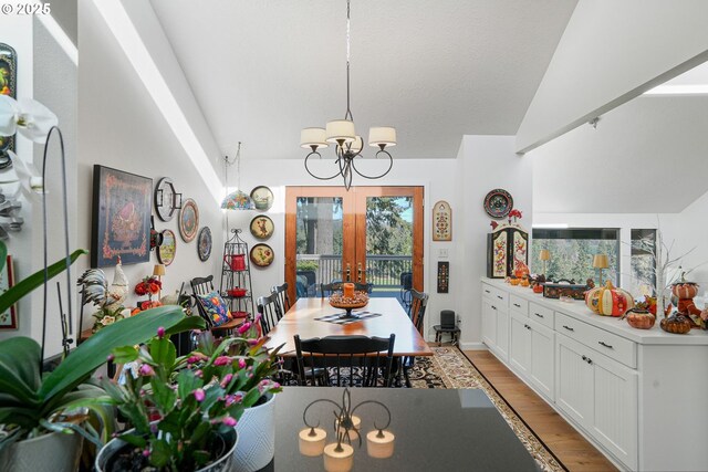 dining room featuring light hardwood / wood-style floors, french doors, vaulted ceiling, and a notable chandelier