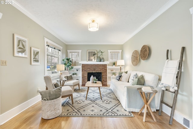 living room featuring baseboards, a brick fireplace, wood finished floors, and ornamental molding