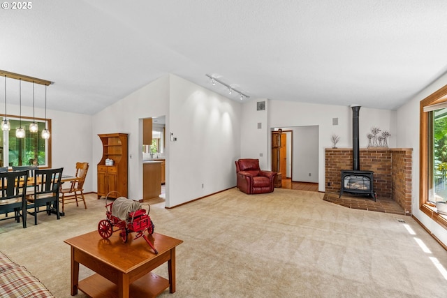 38383 Cartwright Creek Rd, Marcola, OR 97454 - living room with vaulted ceiling, rail lighting, light colored carpet, a wood stove, and baseboards