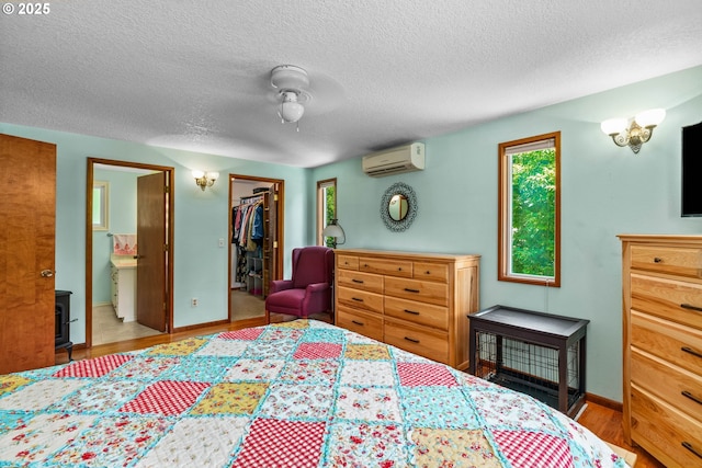 38383 Cartwright Creek Rd, Marcola, OR 97454 - bedroom with a wall mounted air conditioner, a spacious closet, wood finished floors, baseboards, and a textured ceiling