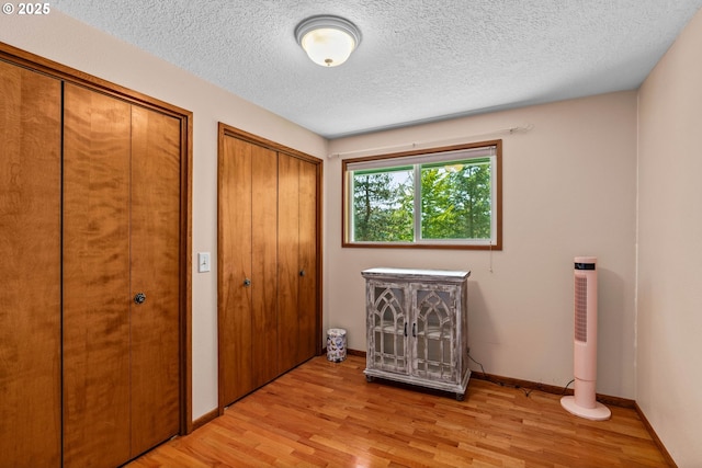 38383 Cartwright Creek Rd, Marcola, OR 97454 - unfurnished bedroom with multiple closets, light wood-style flooring, a textured ceiling, and baseboards
