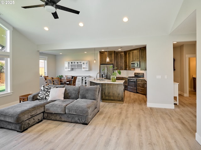 living area with recessed lighting, ceiling fan, light wood-style flooring, and baseboards