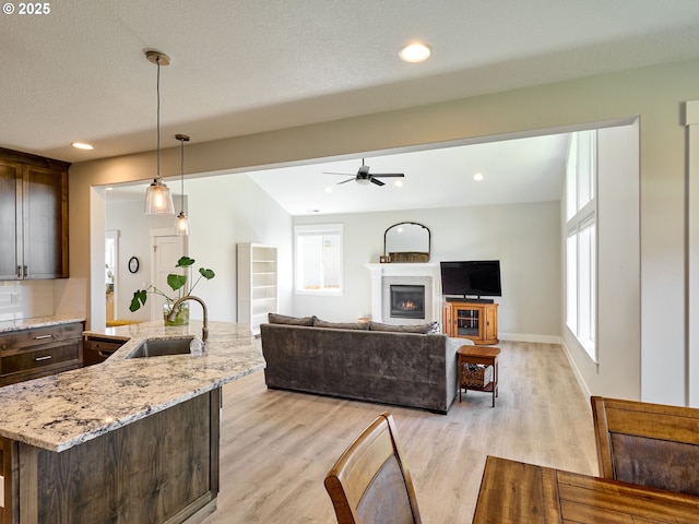 living area with a textured ceiling, recessed lighting, baseboards, a lit fireplace, and light wood-type flooring