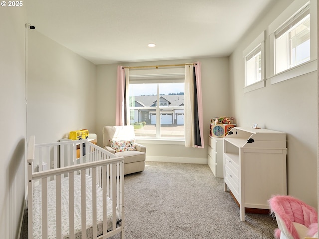 bedroom featuring a crib, multiple windows, carpet, and baseboards