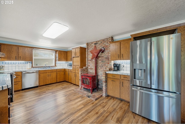 9065 Trask River Rd, Tillamook, OR 97141 - kitchen with stainless steel appliances, brown cabinets, a textured ceiling, tile countertops, and backsplash