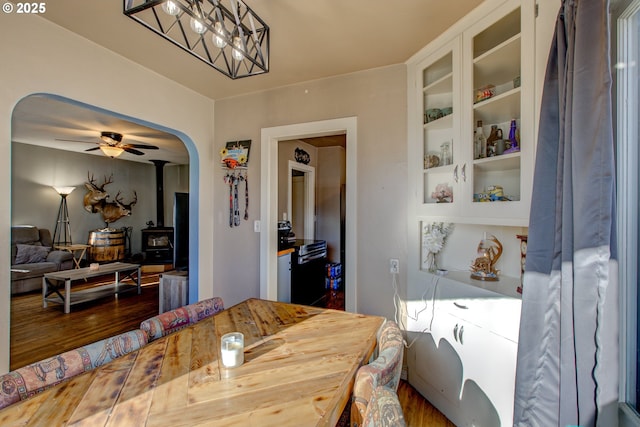 dining area featuring built in features, a wood stove, ceiling fan, and hardwood / wood-style floors