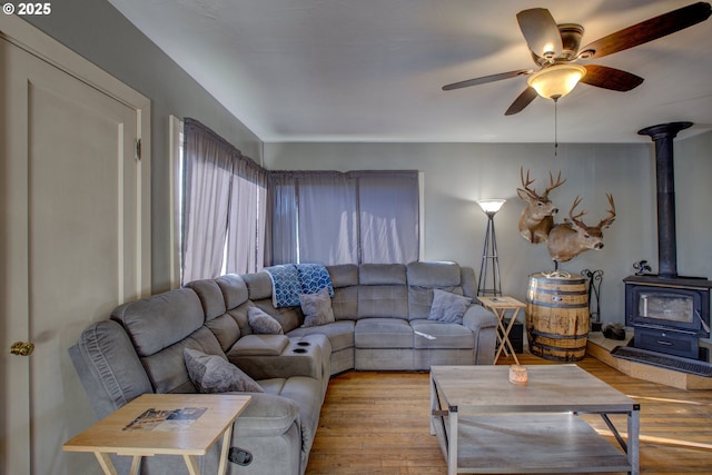 living room featuring a wood stove, ceiling fan, and light hardwood / wood-style flooring