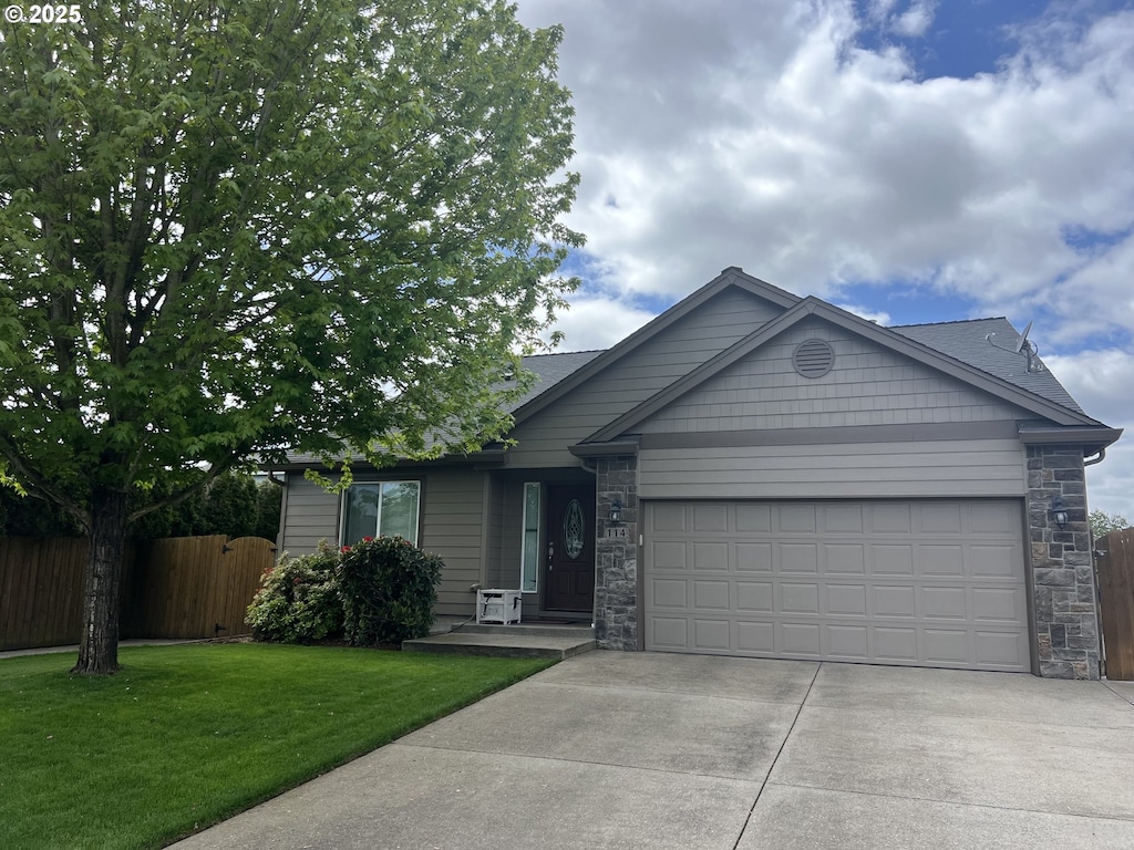 ranch-style home with driveway, a garage, fence, a front lawn, and stone siding