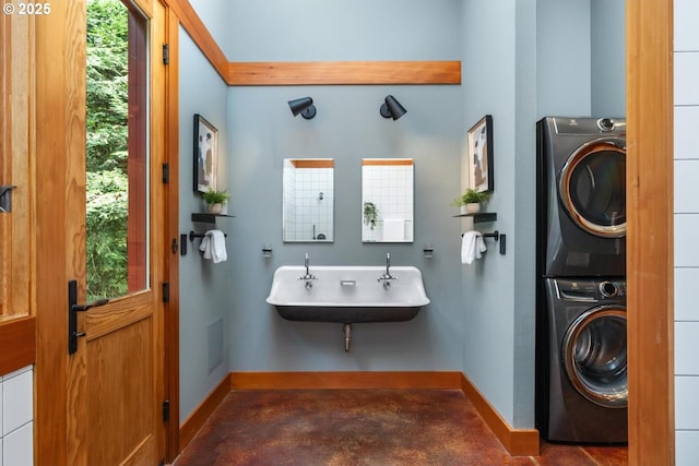 bathroom with estacked washer and dryer, baseboards, finished concrete floors, and a sink
