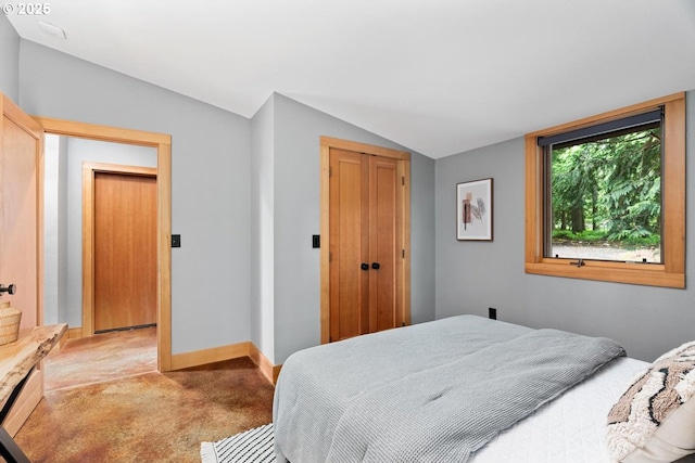 carpeted bedroom with lofted ceiling, a closet, and baseboards