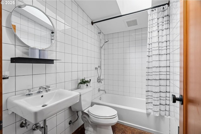 bathroom with tile walls, shower / bath combo with shower curtain, toilet, a sink, and decorative backsplash