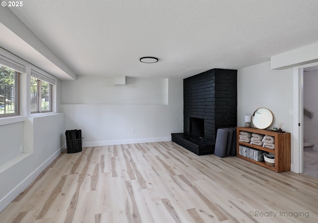 10262 SE 99th Dr, Happy Valley, OR 97086 - unfurnished living room featuring wood finished floors, a textured ceiling, a fireplace, and baseboards