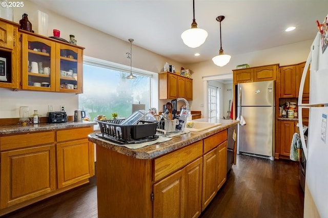 kitchen featuring sink, decorative light fixtures, dark hardwood / wood-style flooring, stainless steel appliances, and a kitchen island with sink