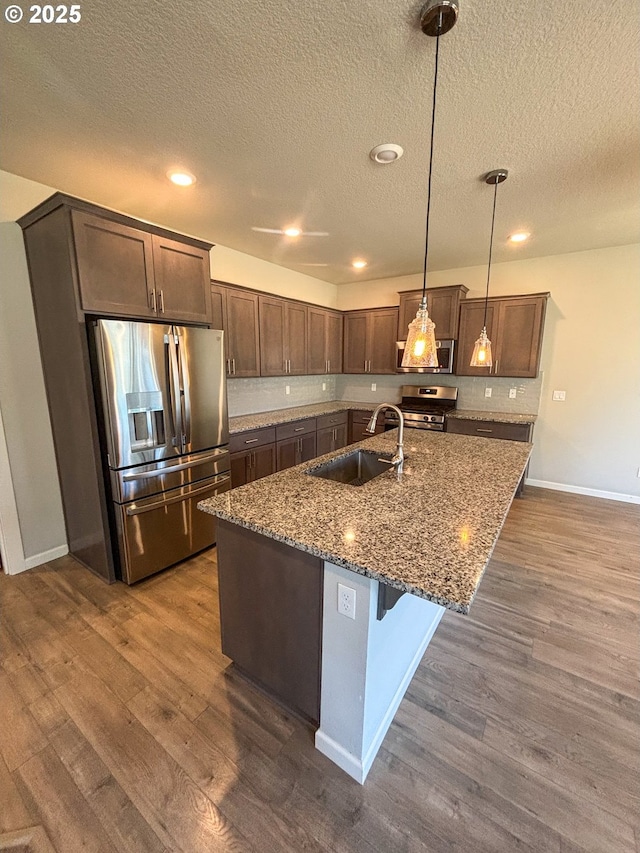 kitchen featuring sink, hanging light fixtures, dark hardwood / wood-style floors, stone counters, and stainless steel appliances