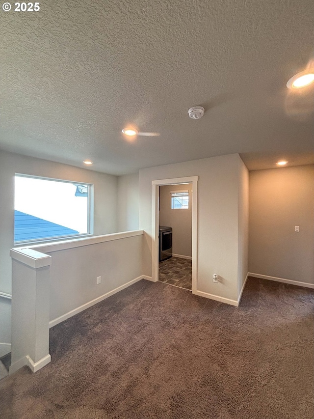 empty room with dark colored carpet and a textured ceiling