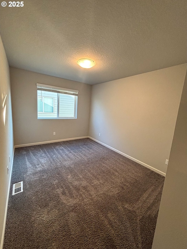 empty room featuring a textured ceiling and dark colored carpet