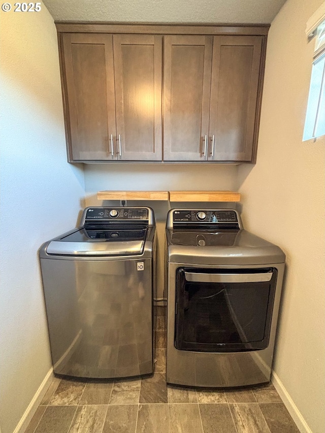 clothes washing area featuring cabinets and separate washer and dryer