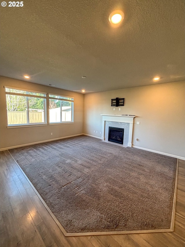 unfurnished living room featuring dark wood-type flooring, a fireplace, and a textured ceiling