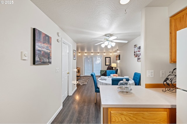 dining space with ceiling fan, dark hardwood / wood-style floors, and a textured ceiling