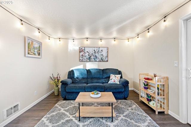 living room featuring dark hardwood / wood-style flooring, a textured ceiling, and rail lighting