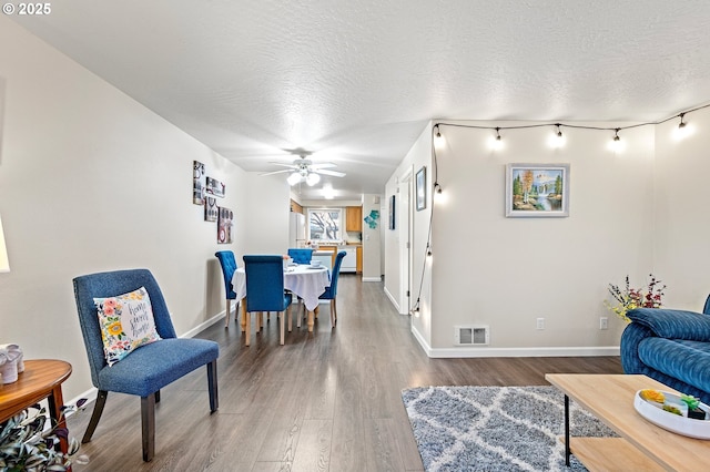 living room with wood-type flooring, ceiling fan, and a textured ceiling