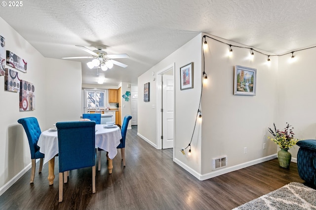 dining space featuring ceiling fan, dark wood-type flooring, and a textured ceiling