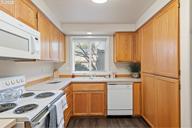 kitchen featuring white appliances, dark hardwood / wood-style floors, sink, and a textured ceiling