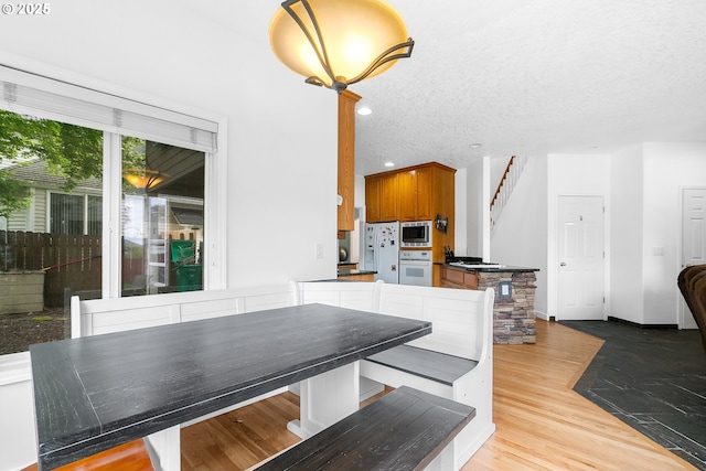 dining area with stairway, light wood-style flooring, recessed lighting, and a textured ceiling